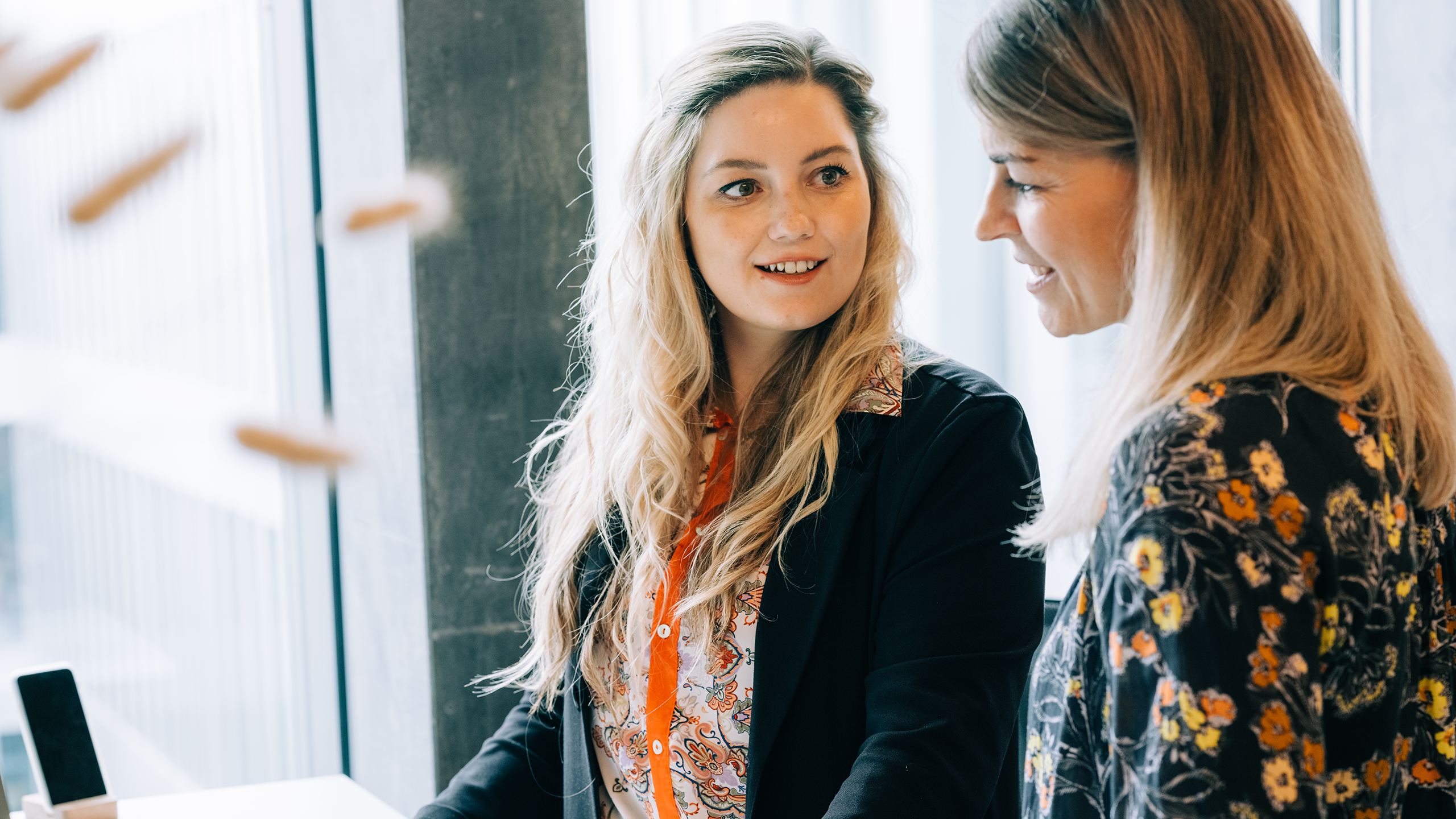 2 junge Damen vor dem Computer besprechen miteinander eine Sache