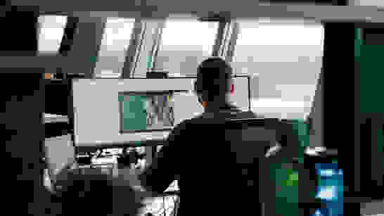 isolutions Datenschutz Privacy Junger Mann von hinten, wie er am PC sitzt und arbeitet