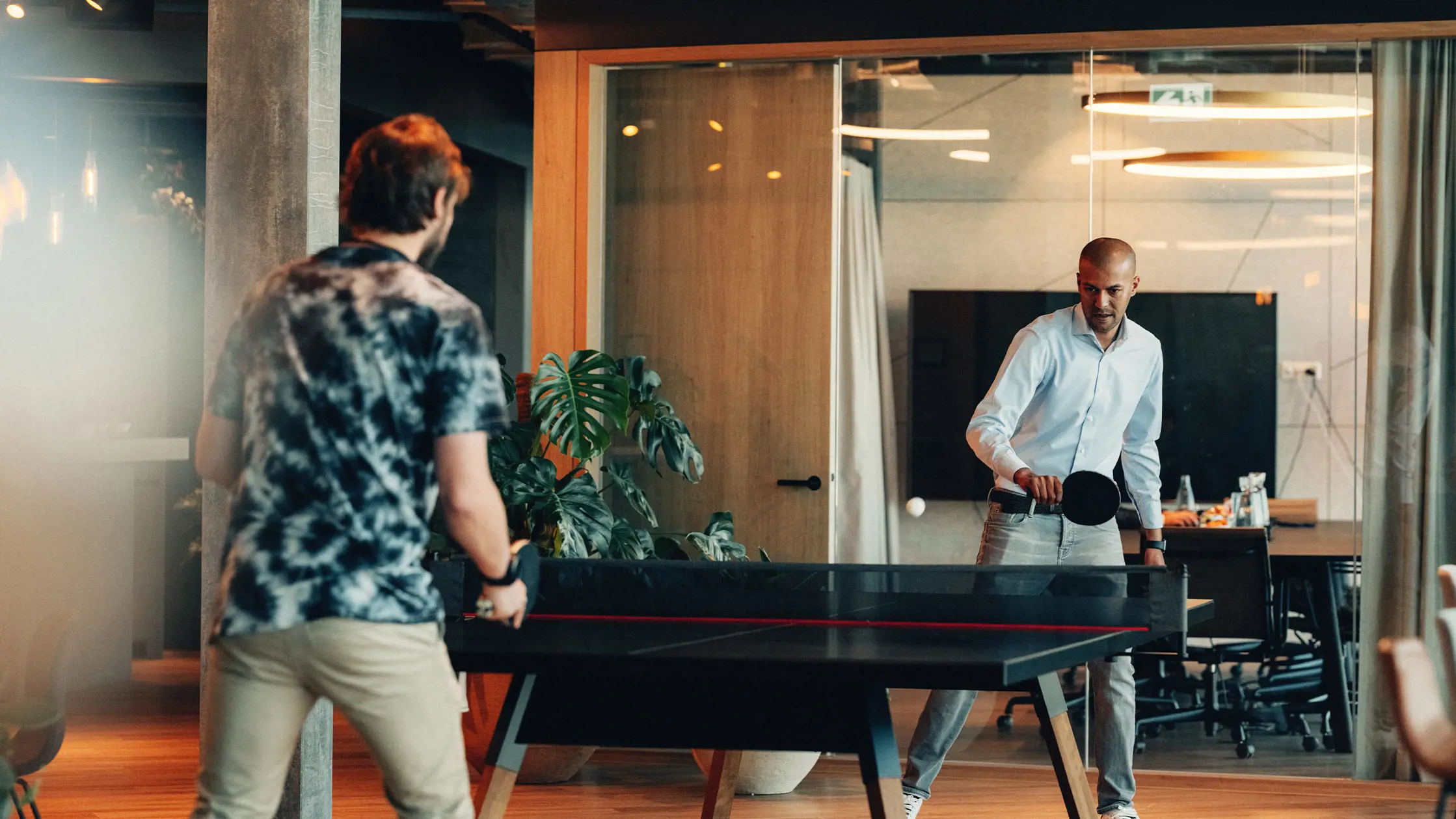 2 jugne Männer spielen gegeneinander Ping Pong in einem modernen Office