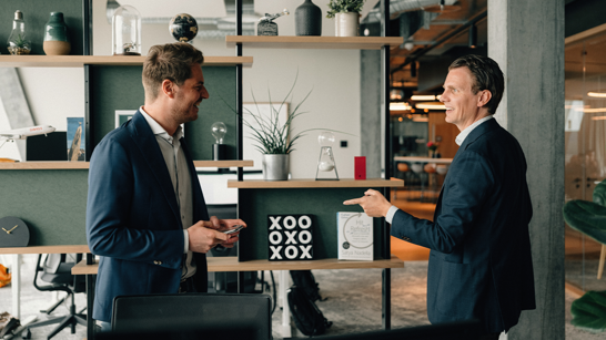 iworkspace Bern Zurich 2 junge Männer unterhalten sich lachend in einem Gang eines offenen modernen Büros