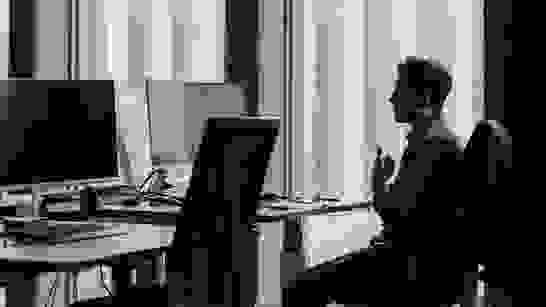 isolutions Impressum Imprint Mann am Telefon mit Headset sitzt alleine an Arbeitsinsel